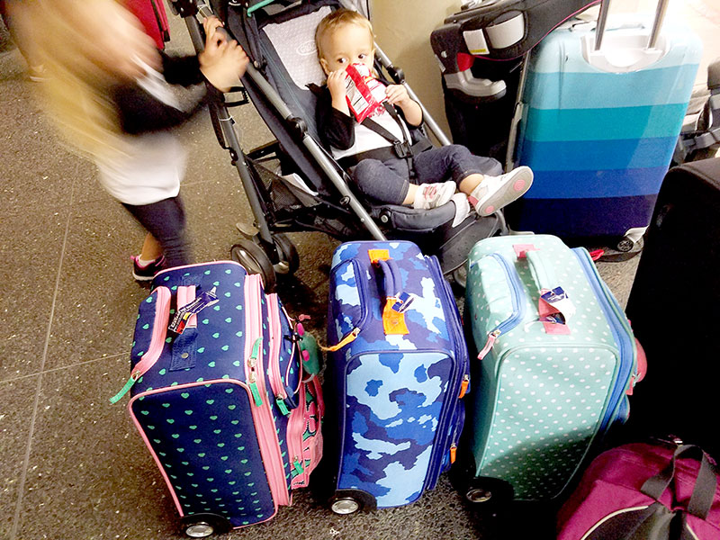 Toddler eating snacks surrounded by suitcases.