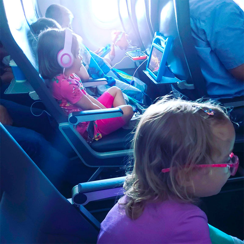 My children flying on an airplane with tablets and headphones